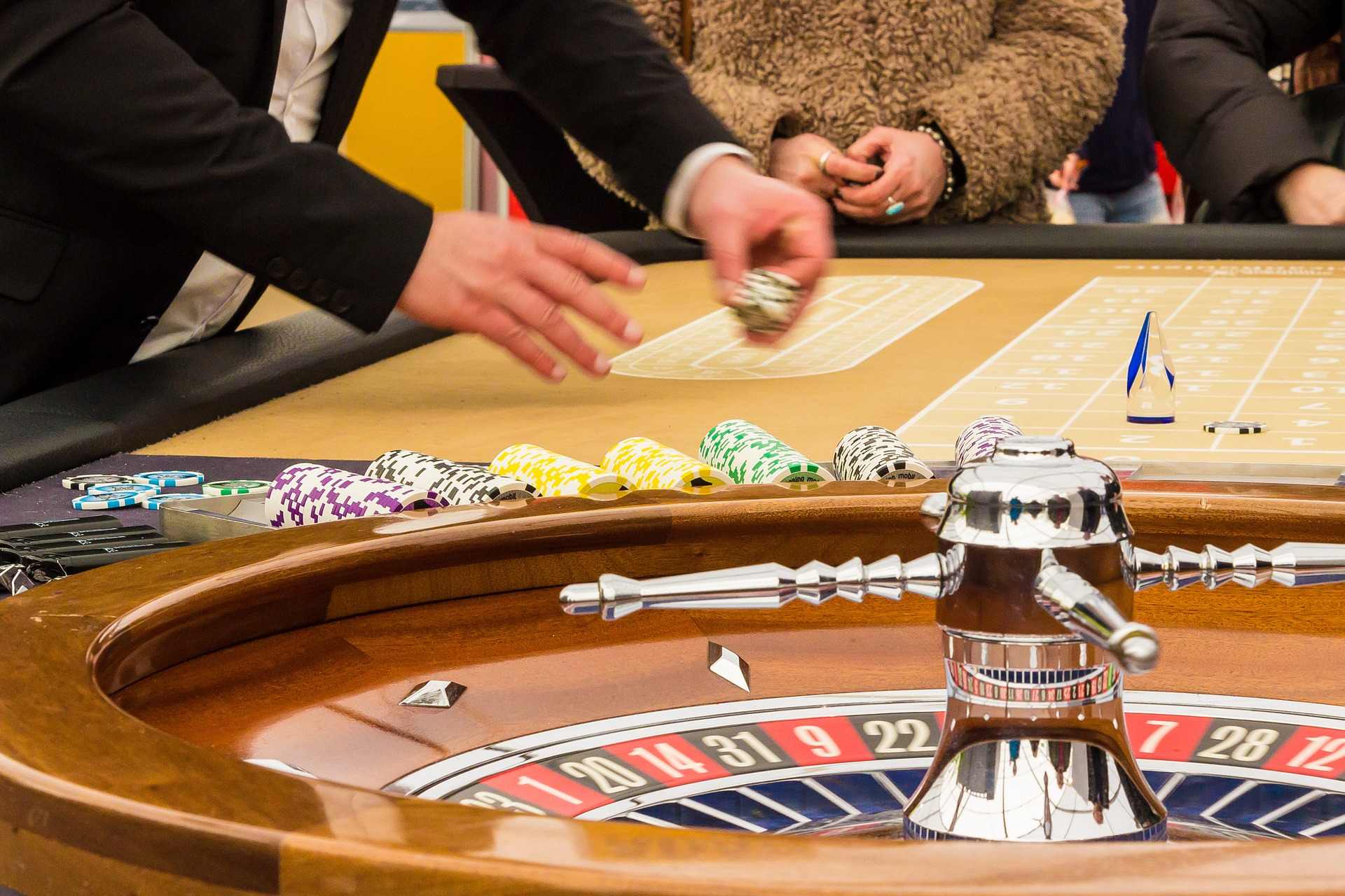 Ein Roulette Kessel, dahinter ein Dealer und Spieler